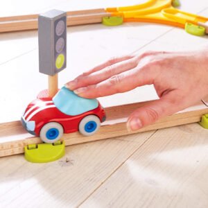 Colorful toy car on a wooden track with a hand pushing with it
